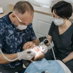 Dentysta odbudowuje ząb jedynkę. Cena zabiegu zależy od metody.