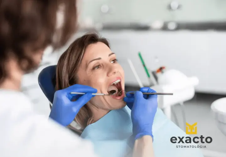 Kobieta w ciąży z bólem zęba u dentysty. Specjalista bada jej jamę ustną.
