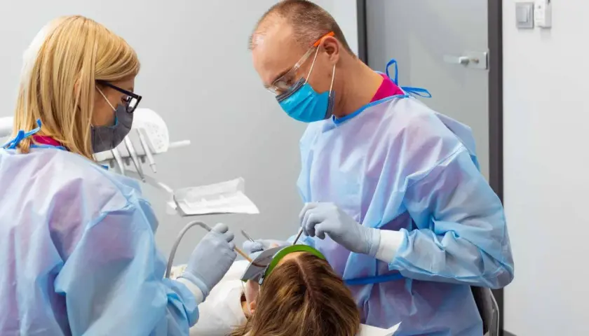 Znieczulenie u dentysty w ciąży. Dwoje stomatologów w fartuchach i maskach wykonuje zabieg u pacjentki.
