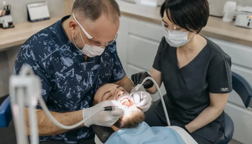 Dentysta odbudowuje ząb jedynkę. Cena zabiegu zależy od metody.