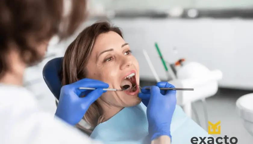 Kobieta w ciąży z bólem zęba u dentysty. Specjalista bada jej jamę ustną.