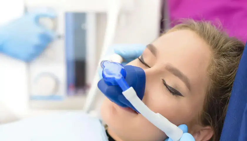 Kobieta z maską do sedacji na twarzy, przygotowana do zabiegu.